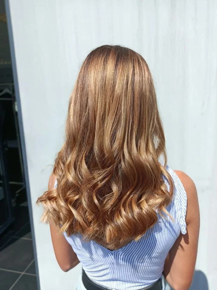 Réalisation balayage caramel sur cheveux longs ondulés